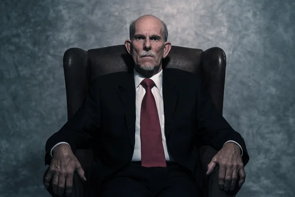 En silla de cuero sentado hombre de negocios senior con barba gris desgaste —  Fotos de Stock