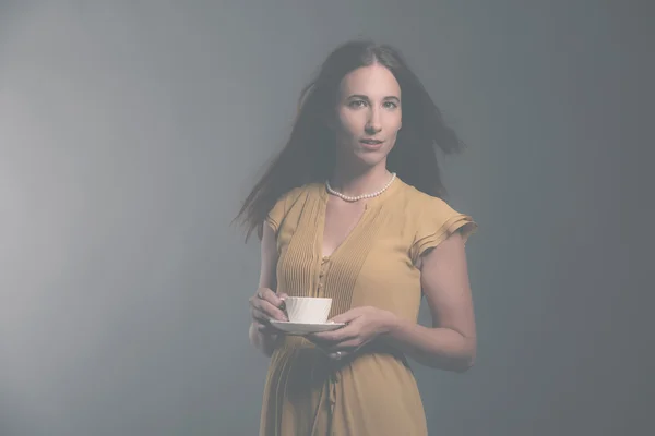 Morena mujer de moda sosteniendo taza de té blanco con Andrés amarillo — Foto de Stock