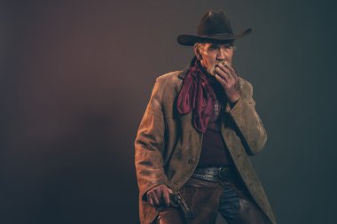 Old rough western cowboy with gray beard and brown hat smoking a clipart