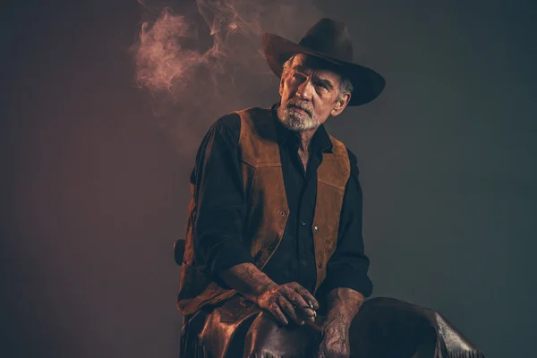 Cigarette smoking old rough western cowboy with gray beard and b — Stock Photo, Image