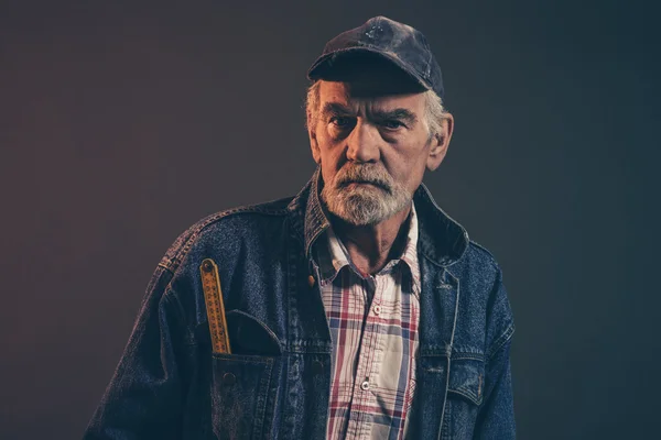 Senior carpenter with gray hair and beard holding yellow measuri — Stock Photo, Image