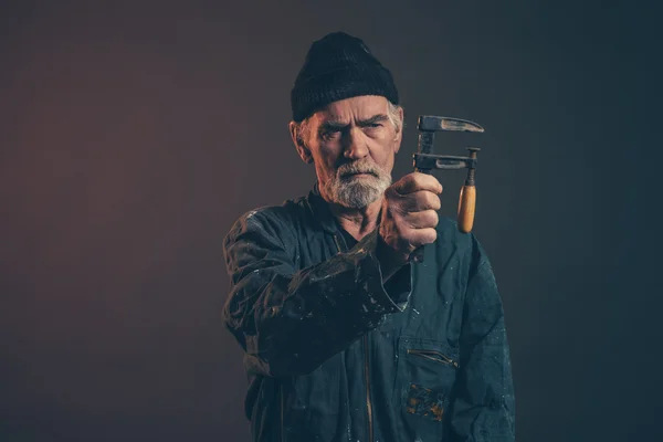 Senior carpenter with gray hair and beard holding clamp wearing — Stock Photo, Image