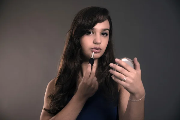 Adolescente con el pelo castaño largo haciendo lápiz labial y sosteniendo encendido — Foto de Stock