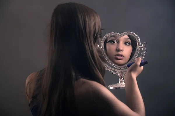 Adolescente chica con el pelo castaño largo haciendo rímel y sosteniendo litt — Foto de Stock