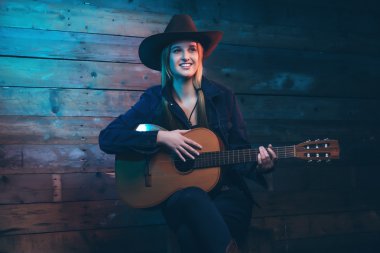 Akustik gitar ile cowgirl country şarkıcısı. Kot giyen 