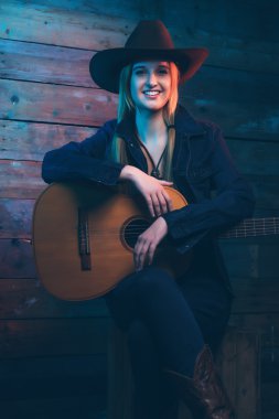 Akustik gitar ile cowgirl country şarkıcısı. Kot giyen 