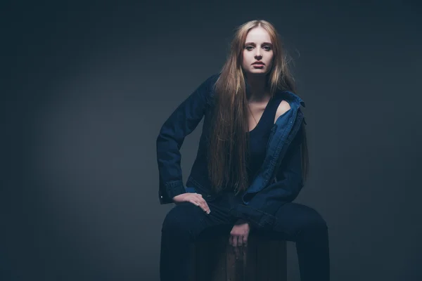 Frau Jeans Wintermode. auf einer alten Holzkiste sitzend. lang — Stockfoto