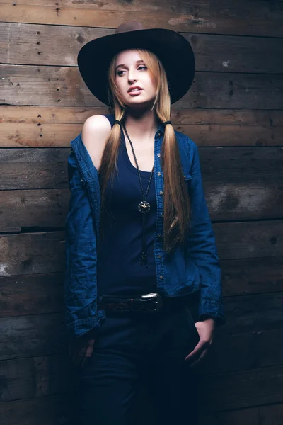 Cowgirl jeans fashion woman with long blonde hair. Standing agai