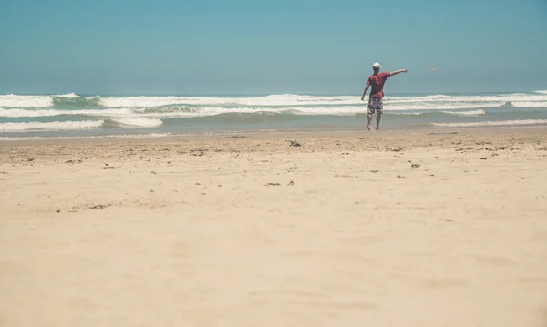 Aktiver Mann mit rotem Hemd am Strand, der mit Frisbee spielt. Summe — Stockfoto