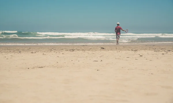 Homme actif avec chemise rouge sur la plage jouant avec frisbee. Somme — Photo