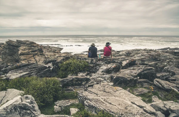 Couple sitting on rock along the wild coast of Tsitsikamma Natio — Stock Photo, Image