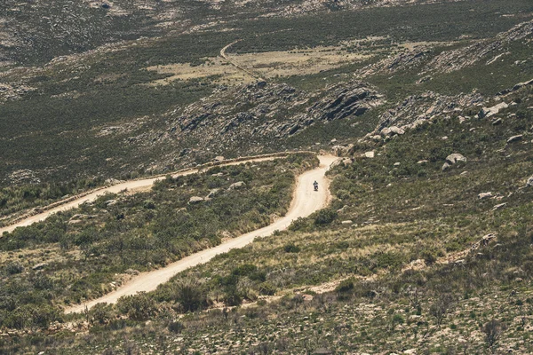 Motorcycle driving on dirt road in Swartberg mountain landscape. — Stock Photo, Image