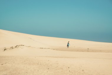 Kadın turist ufuk yürüyüş ile parlak kum tepeleri. CL