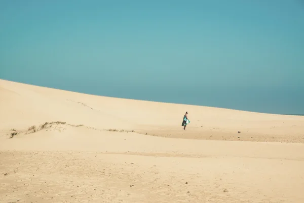 明亮的沙丘与向地平线走来的女游客。Cl — 图库照片