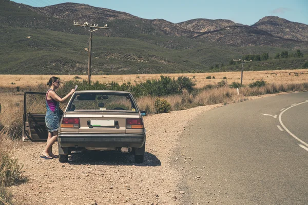 Mujer parada al lado de un auto viejo leyendo un mapa. Swartberg. Occidental. —  Fotos de Stock