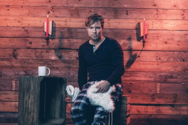 Adam sarışın saç ve sakal kış Pijama giyiyor. Oturma