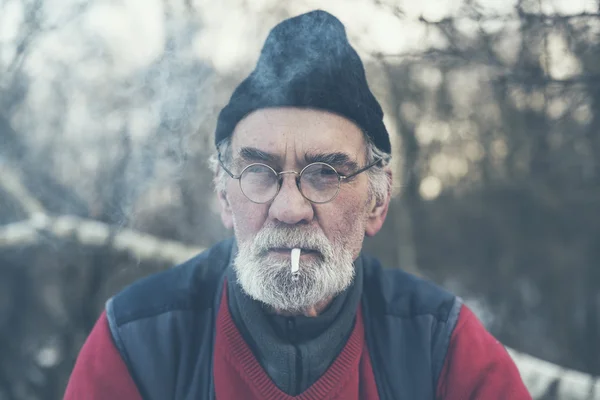 Elderly man enjoying a cigarette outside — Stock Photo, Image