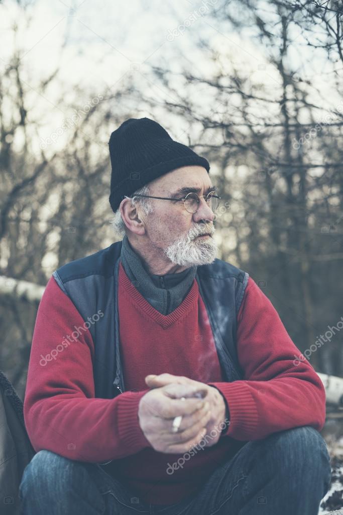 Elderly man smoking in a winter forest