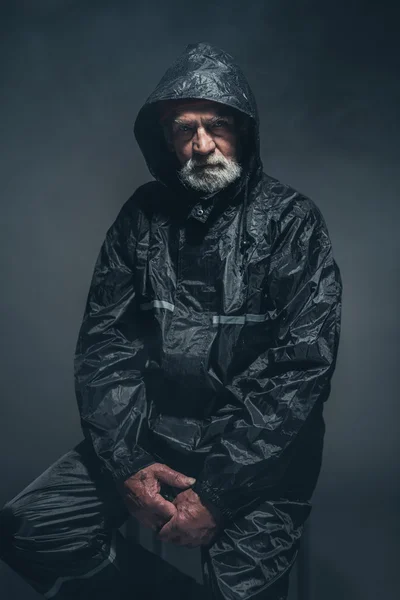 Senior Man in zwarte regenjas — Stockfoto