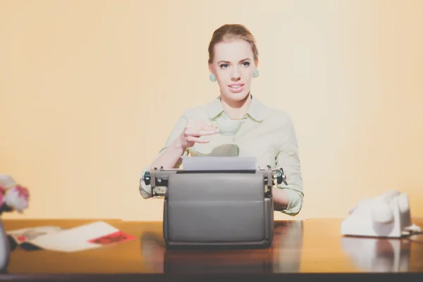 Smiling retro 1950 young secretary woman sitting behind desk dri — Stock Photo, Image