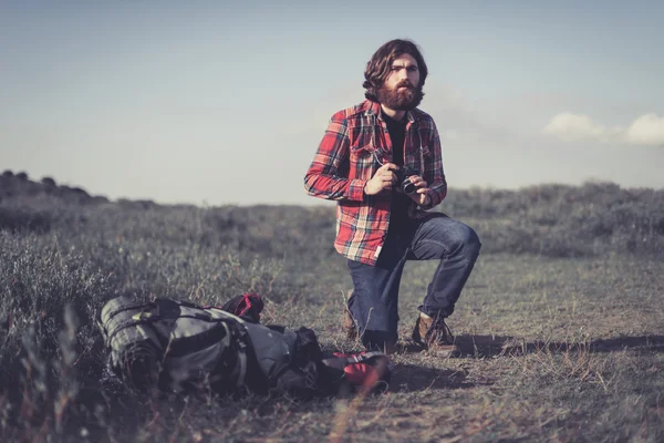 Fotograf på knä vid sidan av sin ryggsäck — Stockfoto