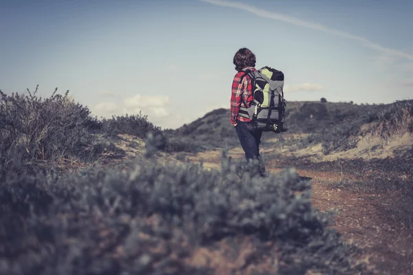 Backpacker går genom kuperad scrub — Stockfoto