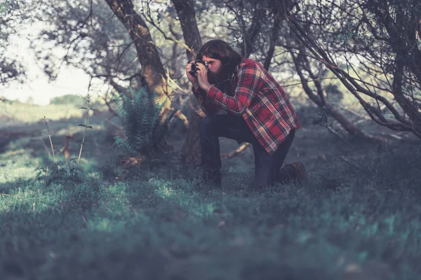 Nature photographer kneeling down to take a shot — Stock Photo, Image