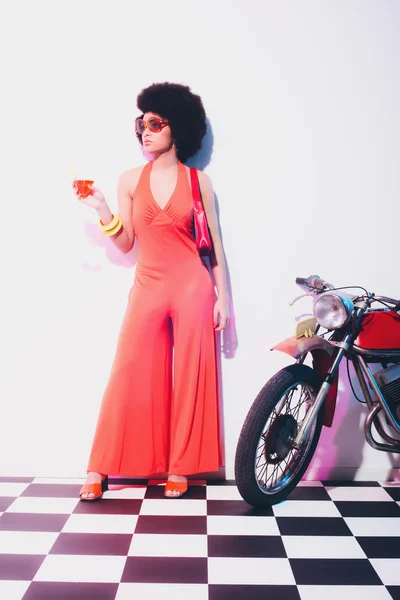 Elegante dama de naranja al lado de una motocicleta —  Fotos de Stock