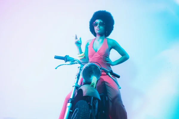 Fumar elegante mulher posando em sua motocicleta — Fotografia de Stock