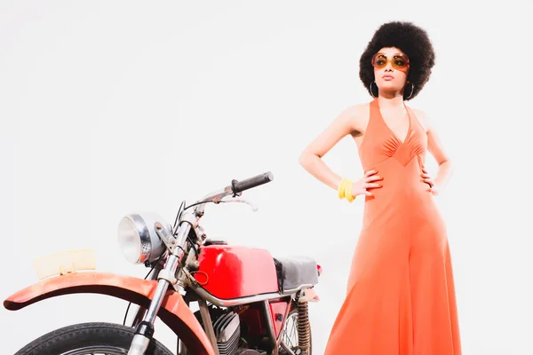 Elegante joven mujer de pie al lado de la motocicleta — Foto de Stock