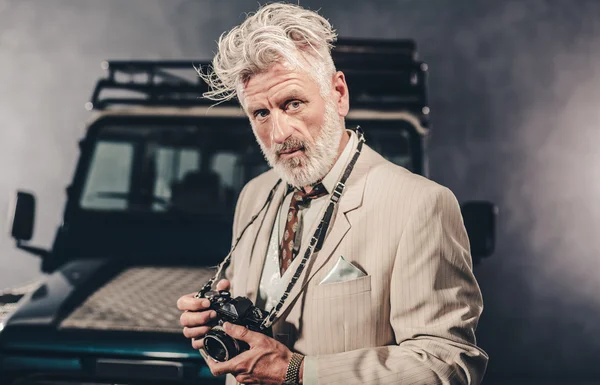 Elegante hombre con cámara contra su vehículo —  Fotos de Stock