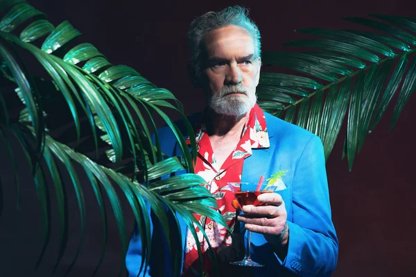 Empresário sério com bebida em uma festa tropical — Fotografia de Stock