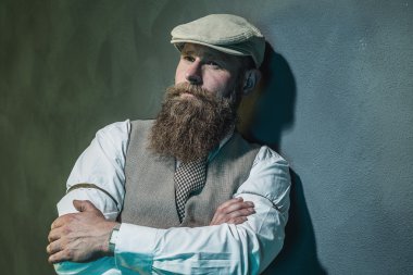 Pensive Man Leaning Against Wall with Arms Crossed