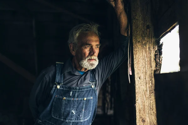 Elderly man staring through window — Stockfoto