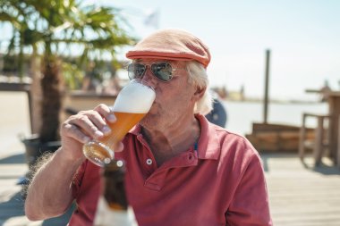 Senior man enjoying cold beer clipart