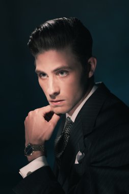 Takım elbise ve kravat çenesini tutan adam.