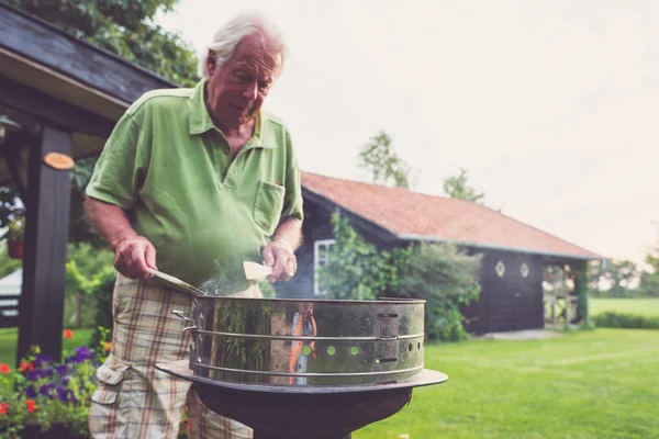 Senior Man voorbereiding van vlees met pensioen — Stockfoto