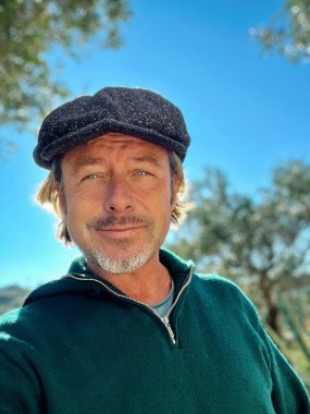 Yünlü gazeteci şapkası ve sakallı, yeşil yünlü süveteri olan, neşeli, haşin bir adam..