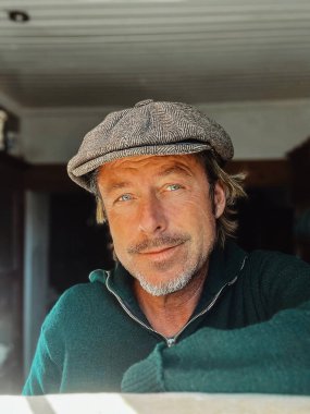 Yünlü gazeteci şapkası ve sakallı, yeşil yünlü süveteri olan haşin bir adam..