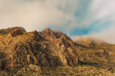 Alçak irtifa bulutlarında dağların sert kayalık yamaçları. Nijar, Almerya, Endülüs, İspanya.