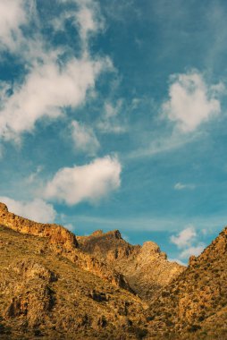 Mavi gökyüzünün altında bulutlu sert kayalık dağlar. Nijar, Almerya, Endülüs, İspanya.