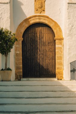 Beyaz sıva duvarlı eski bir İspanyol Endülüs kilisesinin basamakları olan eski ahşap kapı. Huebro, Almerya, Endülüs, İspanya.