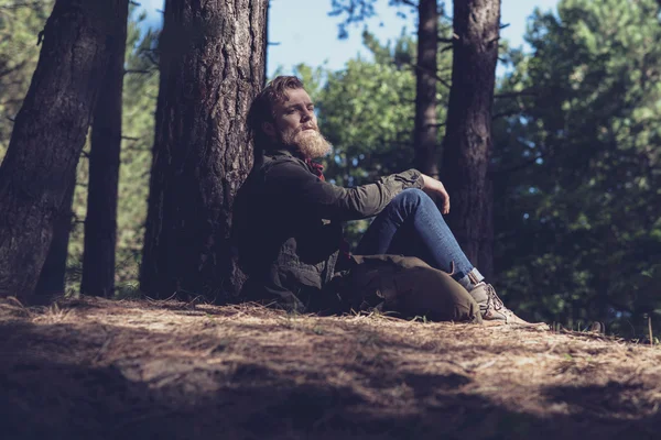 Wandelaar in bos, zittend tegen een boom. — Stockfoto