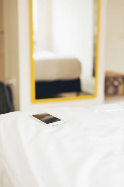 Smartphone na cama do quarto de hotel . — Fotografia de Stock
