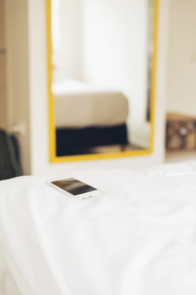 Smartphone op bedje van hotelkamer. — Stockfoto