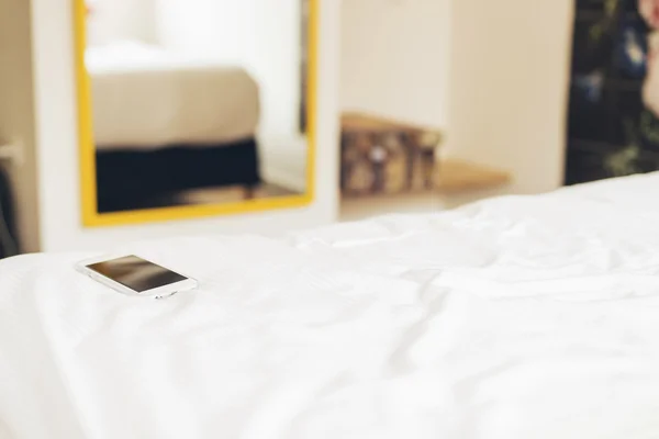 Smartphone na cama do quarto de hotel . — Fotografia de Stock