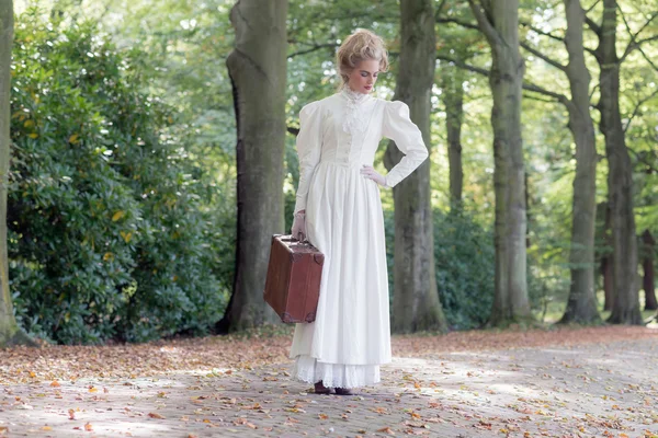 Vintage victorian woman holding suitcase — Zdjęcie stockowe