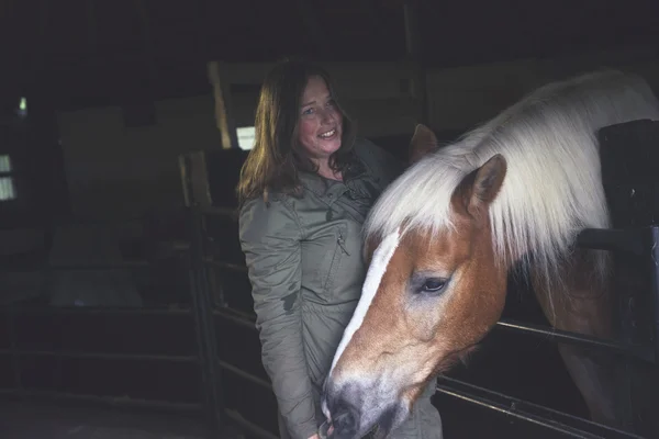 Lachende vrouw permanent door paard — Stockfoto