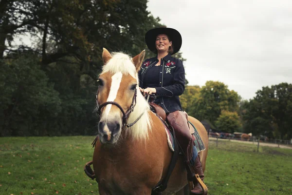 Usmívající se žena krotící koně na koni — Stock fotografie
