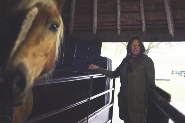 Vrouw bij hek in stal. — Stockfoto